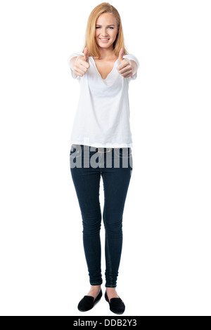 Giovane donna sorridente e dando un doppio pollice su di approvazione e di successo a piena lunghezza ritratto su bianco Foto Stock