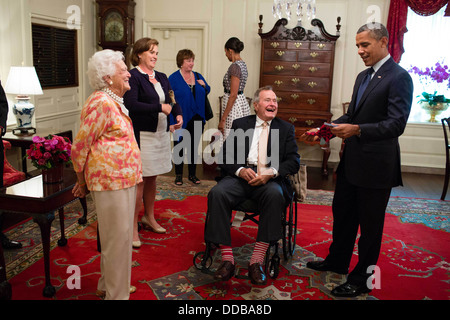 Ex Presidente degli Stati Uniti George H. W. Bush ed ex First Lady Barbara Bush presente il Presidente Barack Obama con un paio di calze nella mappa stanza della casa bianca Luglio 15, 2013 a Washington, DC. Foto Stock