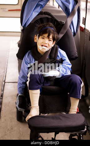 Disabili in età prescolare piccolo ragazzo in sedia a rotelle sul bus Foto Stock