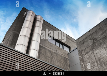 Frammento di astratta di cemento grigio edificio industriale con tubi metallici Foto Stock