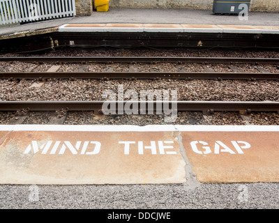 Mente il divario segno sulla stazione ferroviaria platform Foto Stock