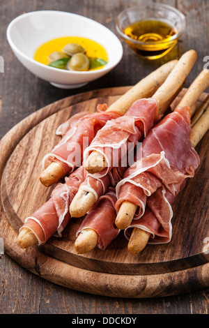 Bastoncini di pane con prosciutto su sfondo di legno Foto Stock