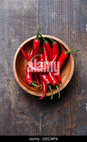 Red Hot Chili Peppers nella ciotola di legno sul vecchio sfondo di legno Foto Stock