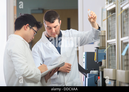 Gli studenti di ingegneria esaminando campioni di riferimento per analizzatore termogravimetrico e prendere appunti in laboratorio di chimica Foto Stock