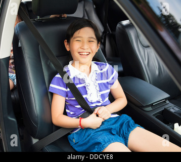 Piccolo felice ragazza seduta in auto con la cintura di sicurezza Foto Stock