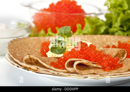 Servita posto impostazione: pancake con caviale rosso e panna acida e verdi Foto Stock