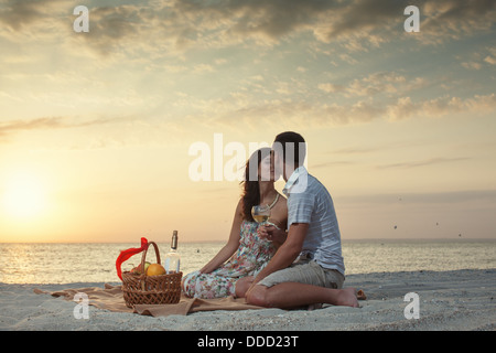 Coppia sulla spiaggia con vino di lusso Picnic durante il bellissimo tramonto. Alba Foto Stock