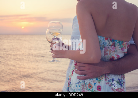 Primo piano di bicchieri di vino bianco durante il tramonto sulla spiaggia. Giovane su un picnic. Foto Stock