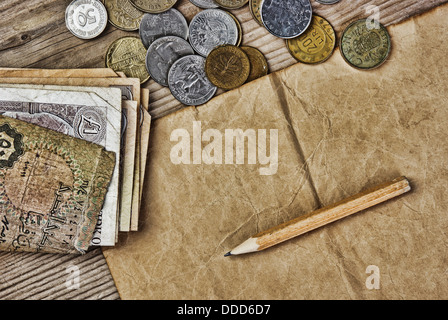 Le vecchie banconote e monete e matita su un tavolo di legno Foto Stock