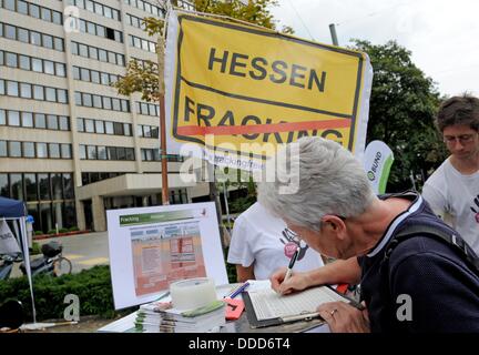 Kassel, Germania. 31 Agosto, 2013. Persone di manifestare contro fracking con firma petizioni di fronte alla sede della più grande della Germania petrolio greggio e gas naturale produttore Wintershall a Kassel in Germania, 31 agosto 2013. Iniziatore della dimostrazione con il motto "Cartellino rosso per Wintershall' è BUND Hessen. Foto: UWE ZUCCHI/dpa/Alamy Live News Foto Stock