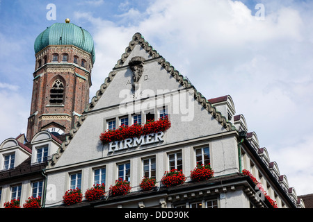 Monaco di Baviera, il department store Hirmer in Neuhauser Strasse, con la Frauenkirche, Baviera, Germania Foto Stock