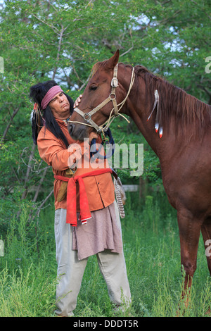 Un American Indian consola il suo cavallo sfregando il cavallo del naso Foto Stock