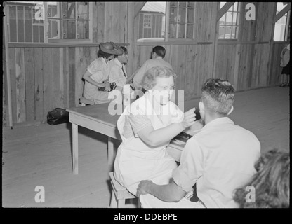 Questa immagine raffigura l'infermiera Hosmer che conduce esami medici preliminari al campo di internamento di Poston in Arizona, evidenziando i controlli sanitari per gli internati appena arrivati. Foto Stock