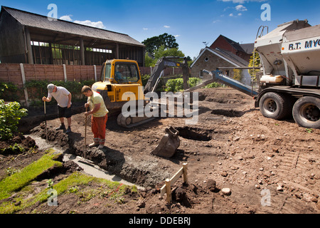 Auto costruzione di casa, costipazione fondazioni in calcestruzzo dopo aver versato utilizzando la benna di scavo volvo Foto Stock