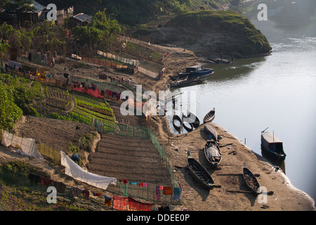 Barche e campi con cibo crescono sulle rive di un fiume in Banderban nelle Chittagong Hill tracts del Bangladesh. Foto Stock