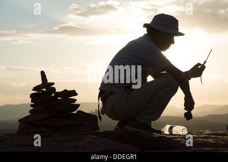 L'uomo Texting con Cairn dietro Aeroporto Vortex Sedona in Arizona Foto Stock