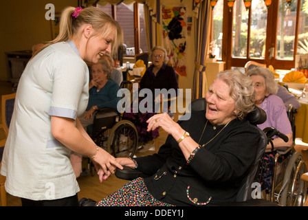 Membro del personale di cura la condivisione di uno scherzo con anziani residenti in una casa di cura, Isleworth, Middlesex, Regno Unito. Foto Stock
