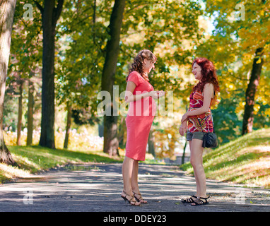 La donna incinta parla con la fidanzata in posizione di parcheggio Foto Stock