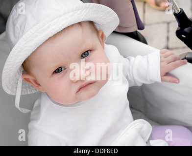 Bambina guarda al di fuori di un passeggino. Foto Stock