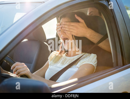 Coppia giovane in auto - l'uomo che copre gli occhi della sua fidanzata Foto Stock