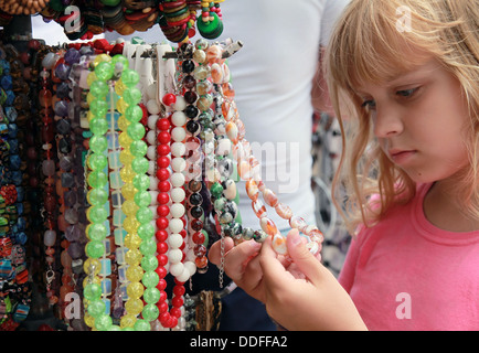 Bimba bionda nel mercato di souvenir ritiene colorate Perline di pietra Foto Stock