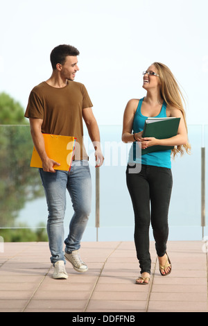 Studenti, coppie o amici universitari che camminano insieme con libri per  l'istruzione e l'apprendimento in campus con borse di studio. Ritratto di  un interracial Foto stock - Alamy