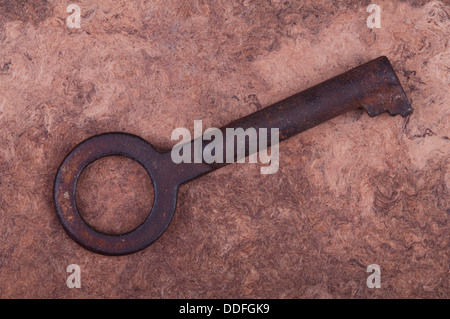 Vecchia chiave arrugginita giacente su pergamena. Close-up. Foto Stock