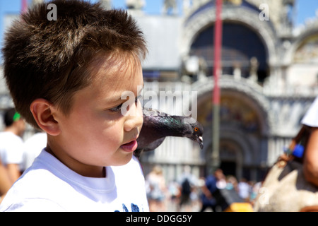 Ragazzo piccioni di alimentazione all'aperto in Piazza San Marco, Venezia Italia Foto Stock