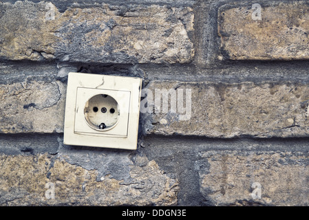 Vecchia plastica del connettore elettrico a spina, presa CA, sul muro di mattoni. Foto Stock