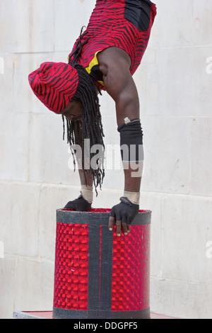 Contortionist street performer Yogi bilanciamento del laser sulla sua casella Trafalgar Square Londra Inghilterra Europa Foto Stock