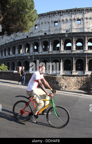 Uomo in Bicicletta Equitazione passato il Colosseo a Roma Italia Foto Stock