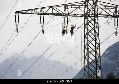 Alta tensione i tecnici del servizio di installazione di una nuova linea elettrica ad alta tensione Foto Stock