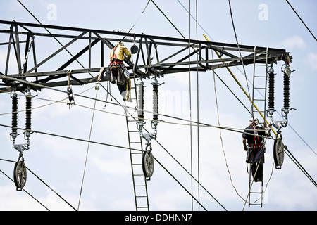 Alta tensione i tecnici del servizio di installazione di una nuova linea elettrica ad alta tensione Foto Stock