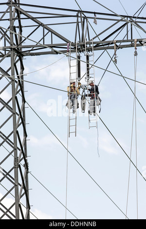 Alta tensione i tecnici del servizio di installazione di una nuova linea elettrica ad alta tensione Foto Stock