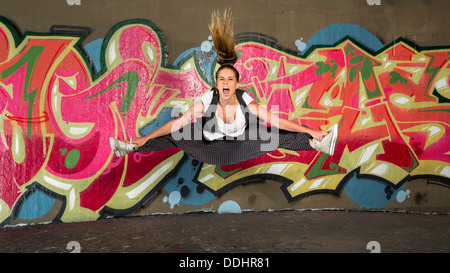 Hip-hop salto ballerino di fronte a un muro con graffiti Foto Stock