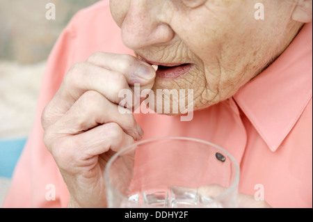 Donna anziana di prendere una compressa di simvastatina (statine) Farmaci che riduce la quantità di colesterolo e di trigliceridi nel corpo Foto Stock