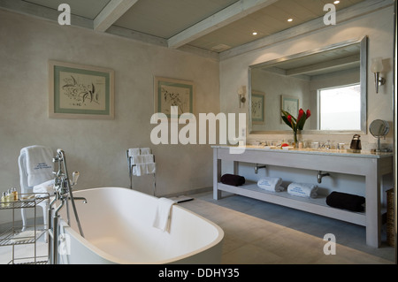 Lavandino doppio in bagno con pavimento piastrellato di marmo e il soffitto a travi e specchio di grandi dimensioni Foto Stock