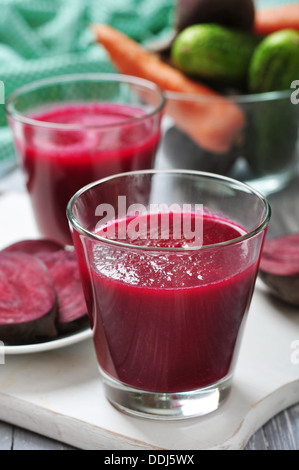 Succo di barbabietola in vetro sul tagliere di legno Foto Stock