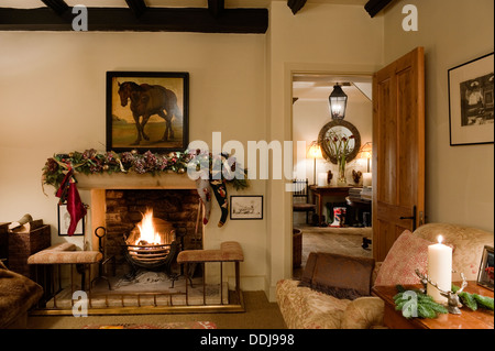 Camino con club parafango nella accogliente soggiorno con stile Howard poltrona e vista attraverso A hall Foto Stock