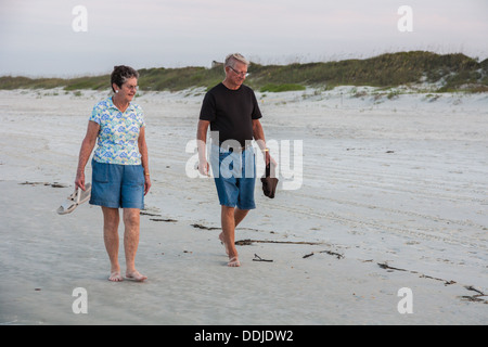 Senior l uomo e la donna portano scarpe camminando e alla ricerca di conchiglie sulla spiaggia a Daytona Beach, Florida Foto Stock