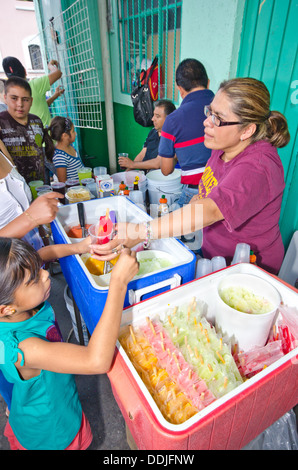 Una donna vende ghiaccioli in un food festival nella città di Puebla. Un bambino sta ricevendo il suo ghiaccio mentre le persone coda dietro. Foto Stock