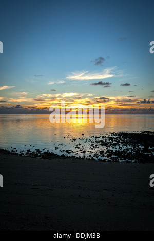 I colori del tramonto con la riflessione sull'oceano a Amuri Beach in Aitutaki Island Isole Cook - Oceano Pacifico del Sud Foto Stock