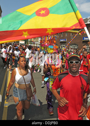 Ballerini in costume holding bandiera da Huddersfield Carnevale 2013 Caraibi africani parade street party Foto Stock