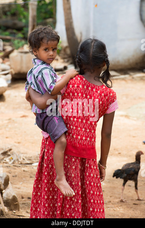 Sorridendo felice rurale villaggio indiano ragazza portando il suo fratello. Andhra Pradesh, India Foto Stock