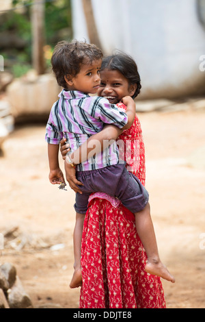 Sorridendo felice rurale villaggio indiano ragazza portando il suo fratello. Andhra Pradesh, India Foto Stock