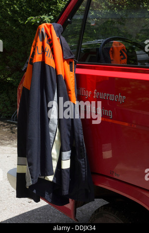 Vigile del fuoco del mantello e pendente da una visione posteriore specchio sul camion dei pompieri, Truchtlaching Chiemgau, Alta Baviera Germania Europa Foto Stock