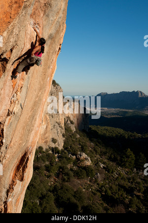 Vista laterale dello sport femminile scalatore. donna leader di calcare verticale Parete di roccia. arrampicata su coastland turco. geikbayiri, Antalya. Foto Stock