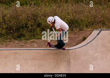 Ragazzo giovane eseguono acrobazie su uno scooter Foto Stock