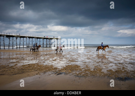 Passeggiate a cavallo sulla spiaggia di Saltburn in riva al mare Foto Stock