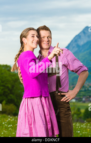 Coppia felice in abito tradizionale è in piedi nel prato con panorama di montagna Foto Stock